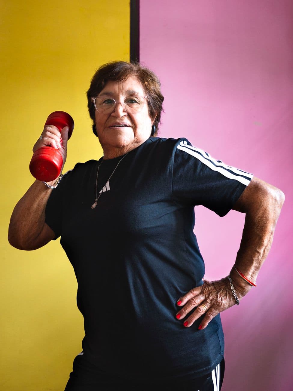 Une femme d'environ 60 ans souriante, assise sur un canapé avec une tasse de thé, regardant par la fenêtre avec une expression sereine et déterminée.
