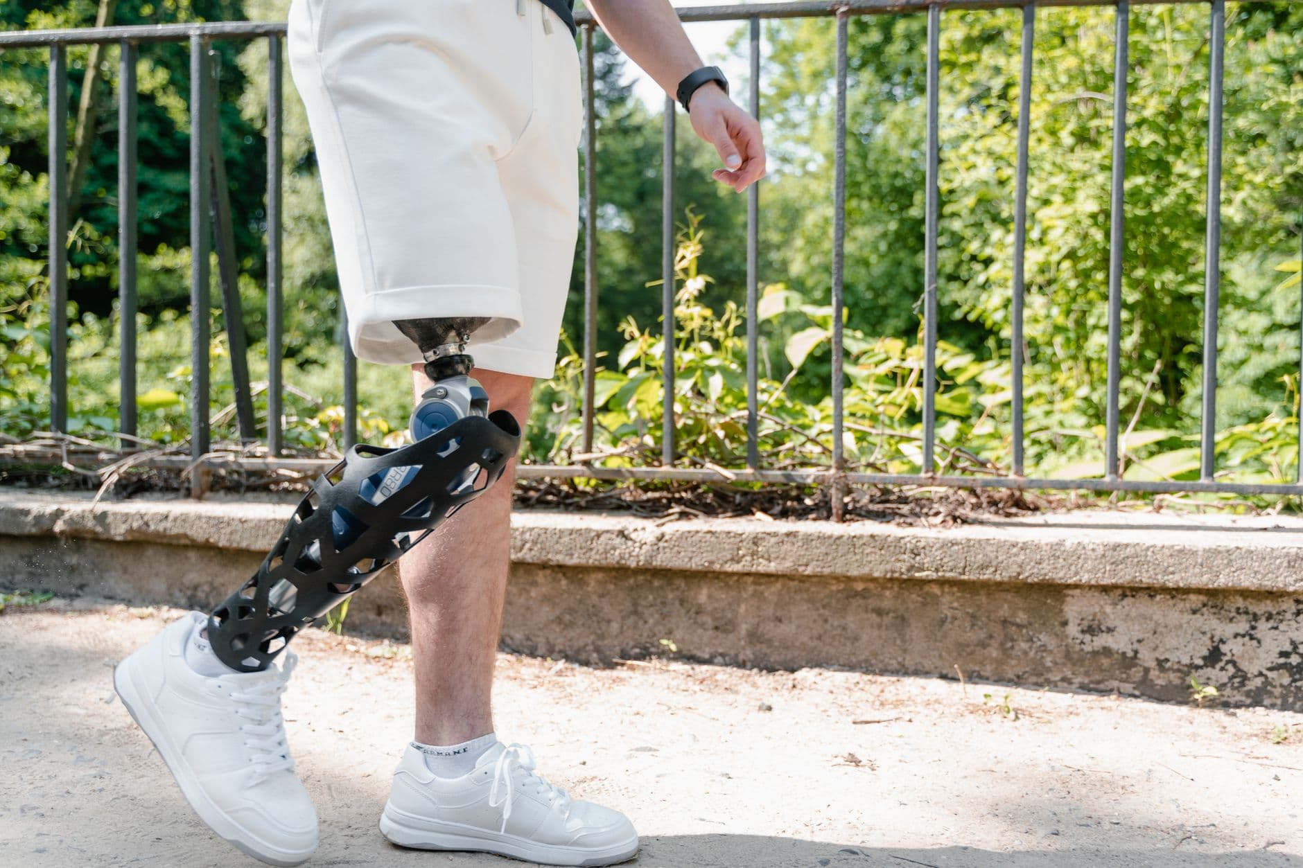 Personne âgée marchant avec des cannes anglaises sur un chemin de parc, accompagnée d'un proche, par une journée ensoleillée.