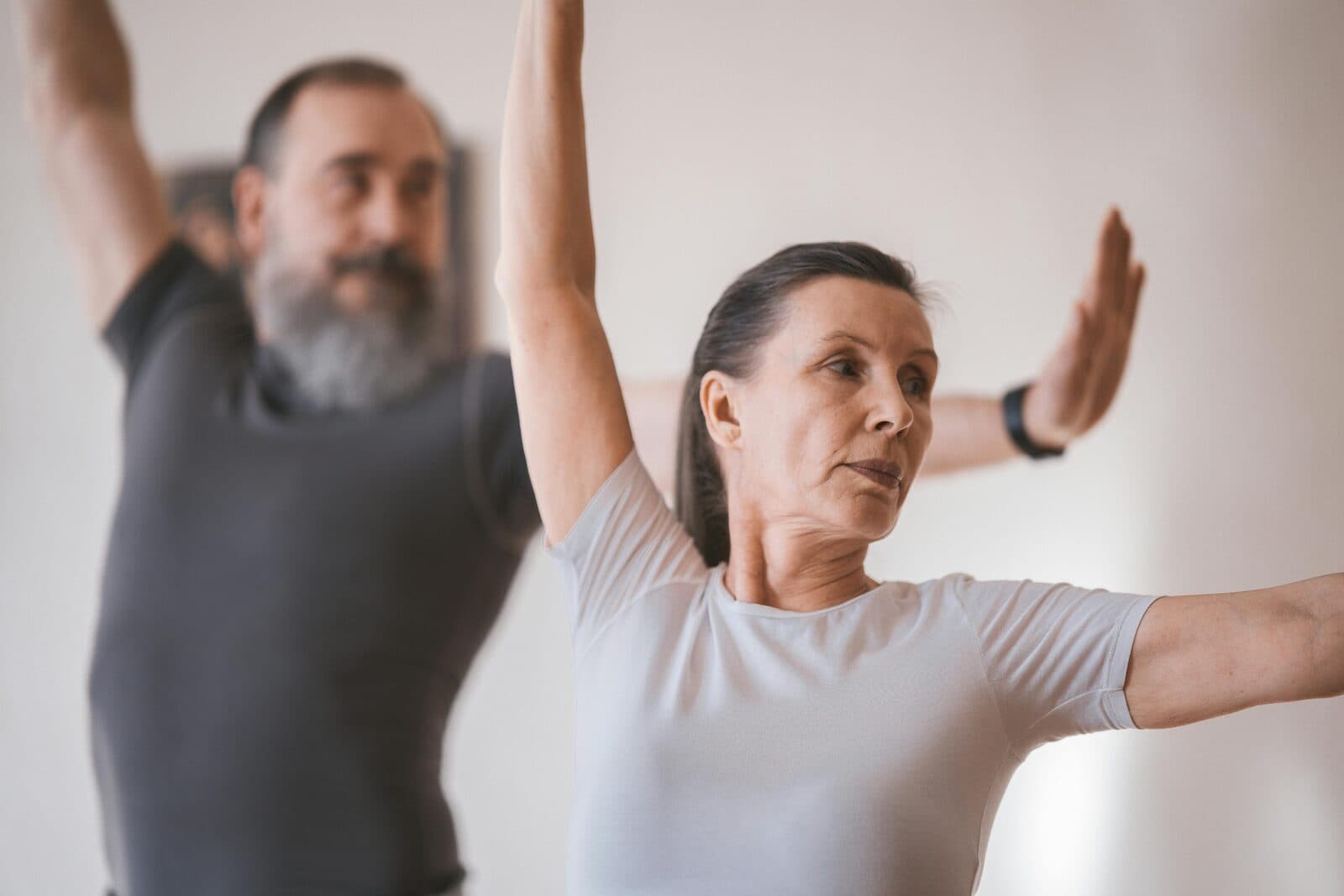 Couple senior en pratique de yoga doux, bras tendus en posture du guerrier
