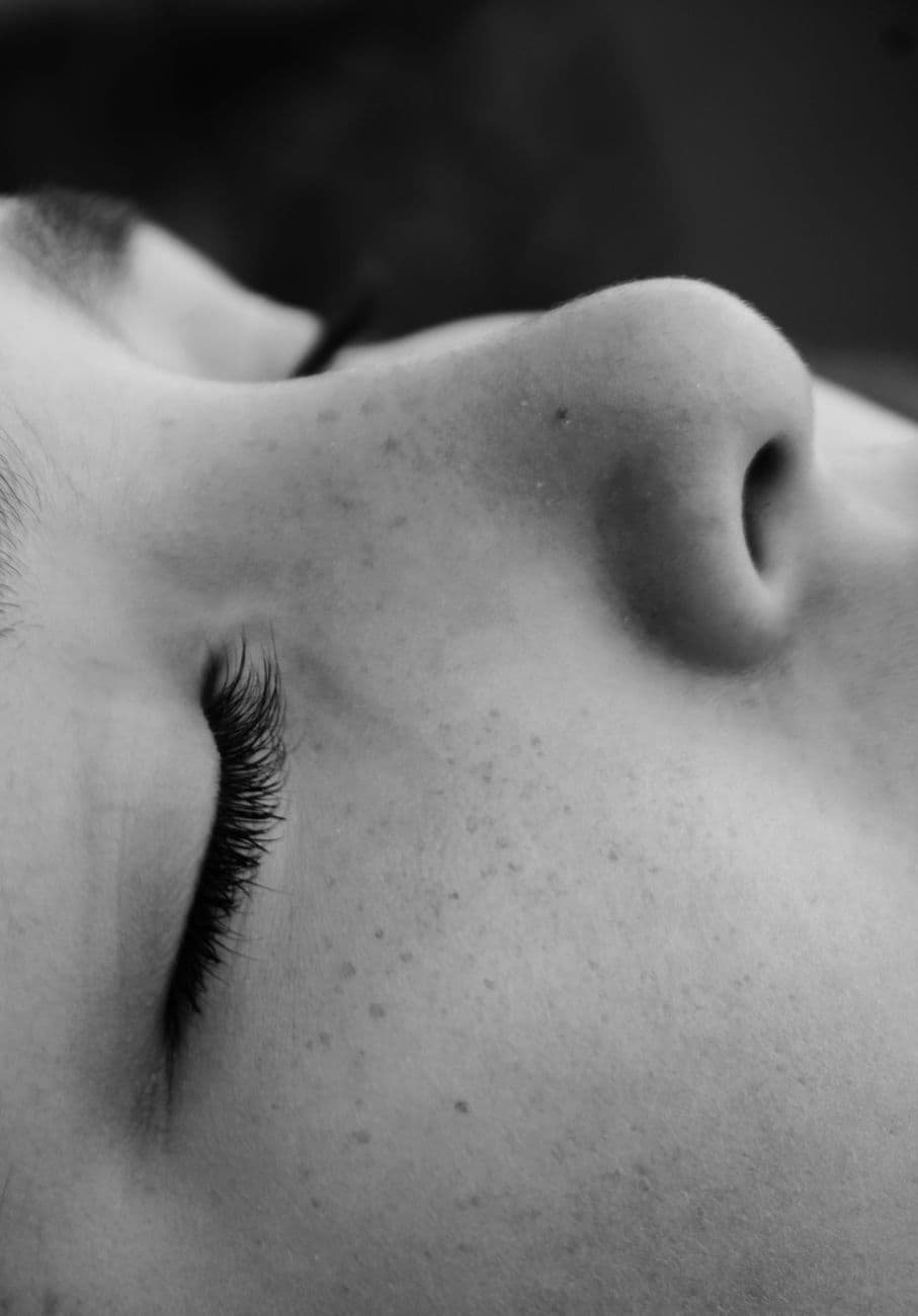 Personne âgée allongée sur le dos dans un lit, les yeux fermés, respirant profondément avec une expression sereine, lumière tamisée de chevet.