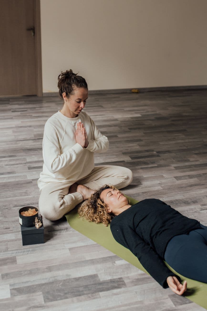 Une personne âgée assise sur un canapé, les yeux fermés, en train d’écouter une méditation guidée avec des écouteurs, dans une pièce calme et lumineuse.