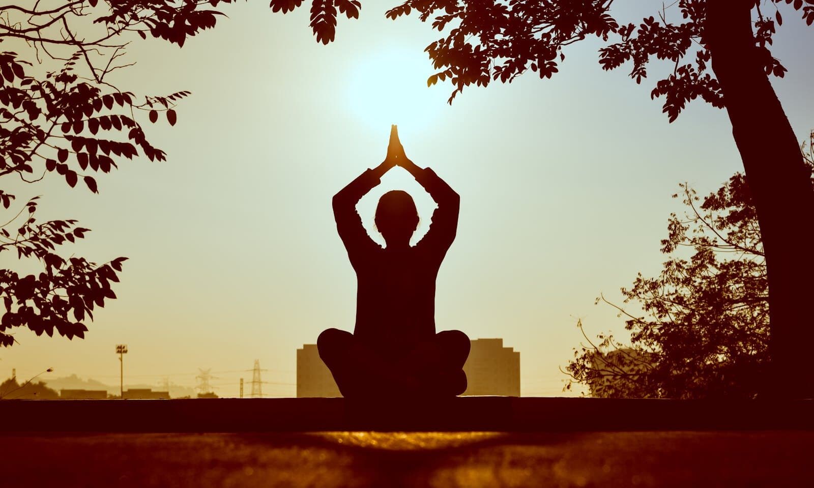 Silhouette d'une personne en posture de méditation au lever du soleil