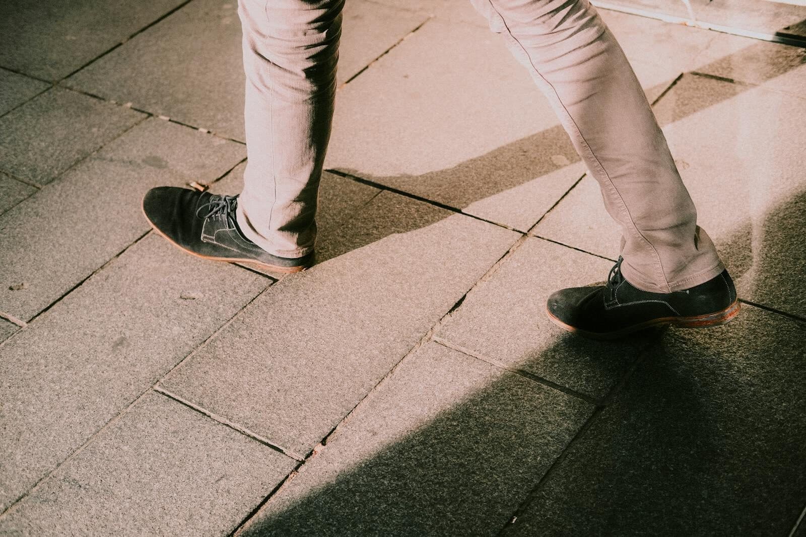 Pieds en chaussures de ville marchant sur un sol pavé en milieu urbain