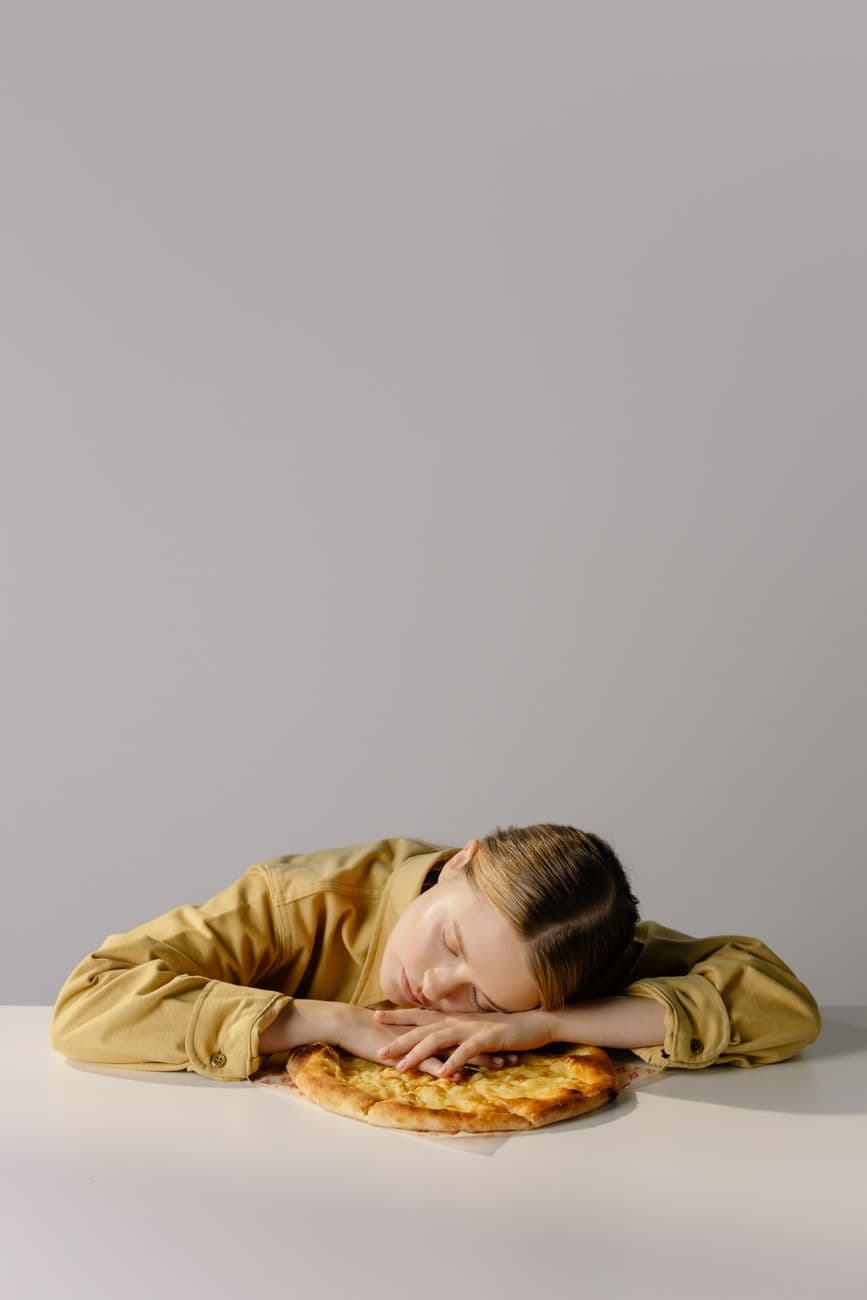Personne âgée préparant une assiette de légumes cuits et de poisson dans une cuisine chaleureuse, avec une tasse de tisane posée à côté.