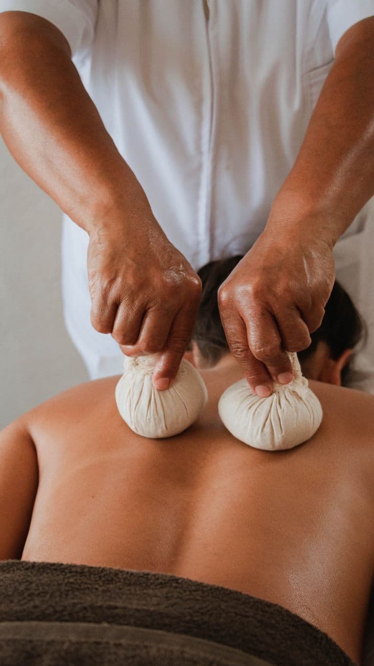 Personne assise sur une chaise, les yeux fermés, une main posée sur le ventre et l'autre sur la poitrine, en train de pratiquer une respiration profonde pour détendre le cou et les épaules.